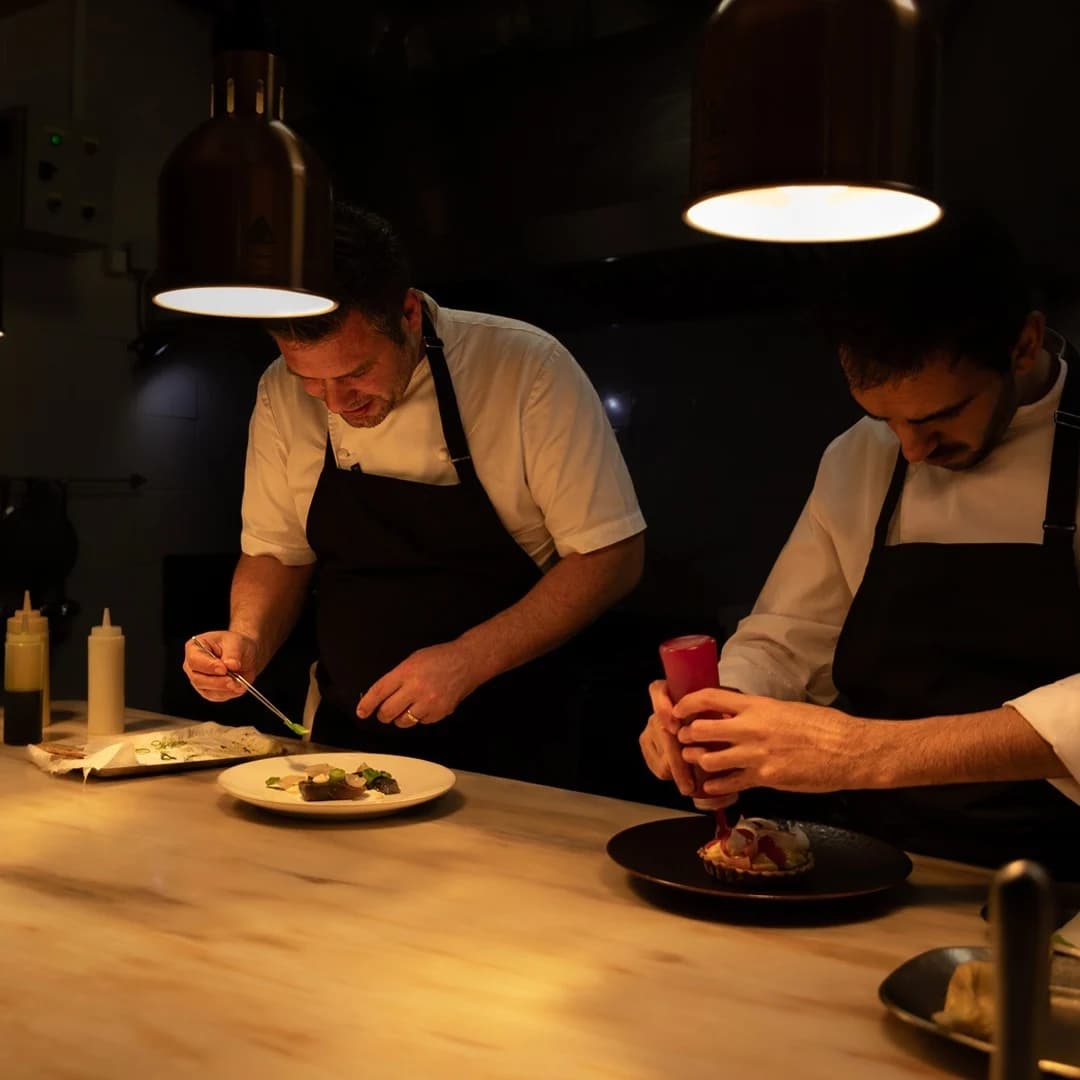Dois cozinheiros a finalizar pratos na cozinha do Mesa 15